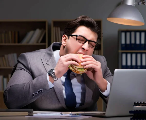 Affärsmannen sent på kvällen äter en hamburgare — Stockfoto