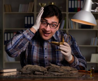 Arkeolog geç saatlere kadar ofiste çalışıyor.