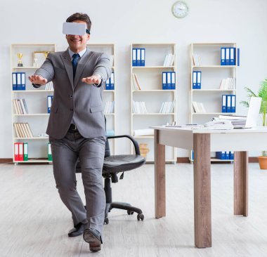 Ofiste egzersiz yapan işadamı VR gözlüğü takıyor.