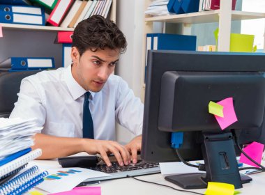 Ofiste kitap ve kağıtlarla çalışan bir işadamı.