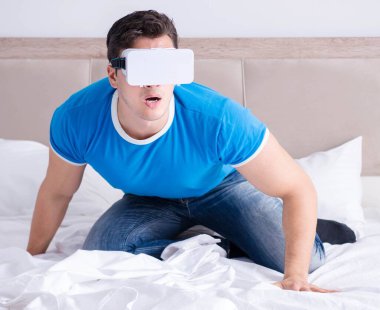 Yatakta sanal gerçeklik başlığı takan genç bir adam.