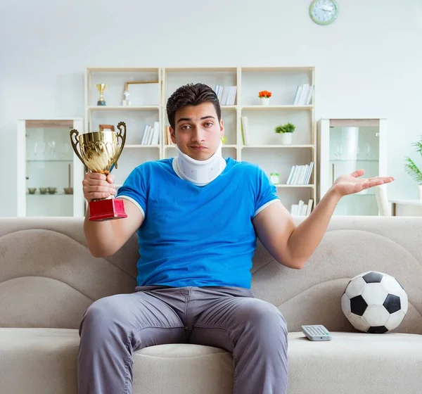 Mężczyzna z kontuzją szyi ogląda piłkę nożną w domu — Zdjęcie stockowe
