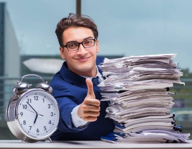 Yığınla evrak işi ve alarm sistemi olan bir iş adamı.