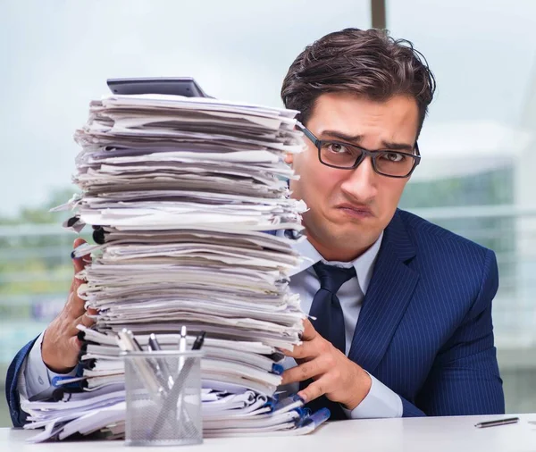 Empresário com pilha de papelada no escritório — Fotografia de Stock