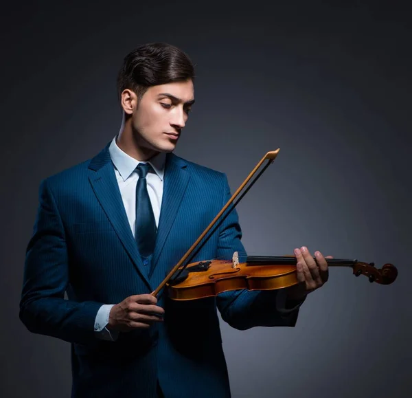 Mladý muž hraje na housle v tmavé místnosti — Stock fotografie