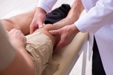 Deneyimli doktor travmatolog genç erkek hastayı muayene ediyor.