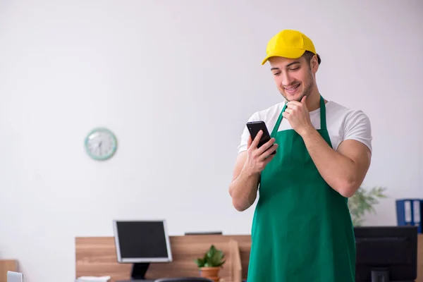 Jovem empreiteiro limpando o escritório — Fotografia de Stock