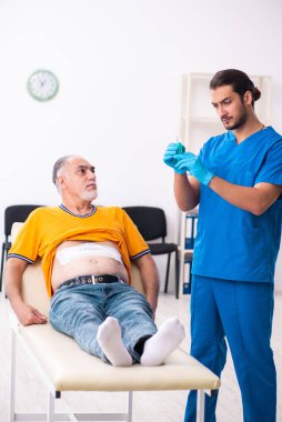 Yaşlı adam genç erkek doktoru ziyaret ediyor.