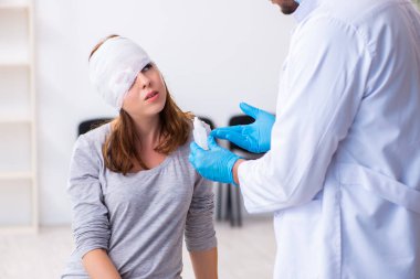 Genç baş yaralı kadın genç erkek doktoru ziyaret ediyor.