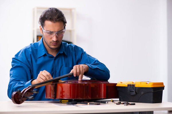 Молодой ремонтник чинит виолончель