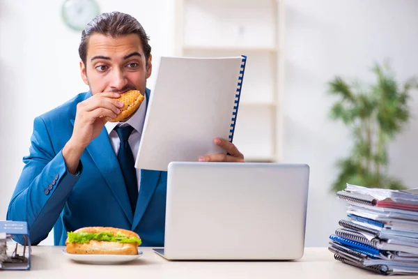 Jeune employé masculin prenant son petit déjeuner sur le lieu de travail — Photo