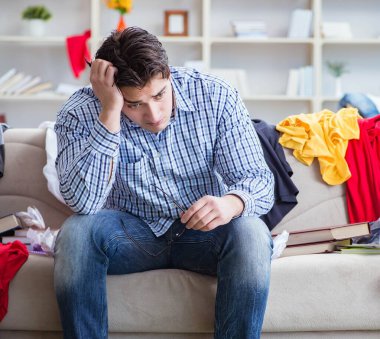 Genç adam dağınık bir odada çalışıyor.