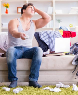 Dağınık odada çalışan genç adam.