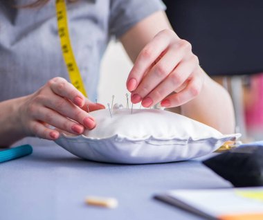 Kadın terzi dikiş dikmek için dikiş dikiyor.