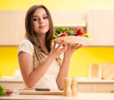 Genç bayan mutfakta salata hazırlıyor.