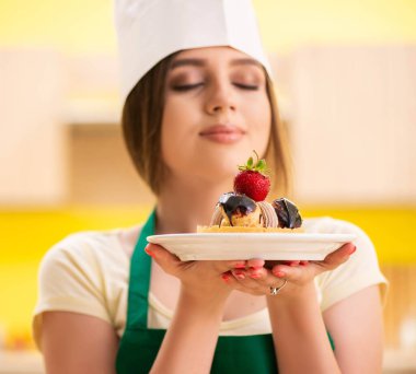 Genç aşçı mutfakta kek pişiriyor.