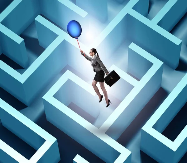 Businesswoman escaping from maze on balloon — Stock Photo, Image