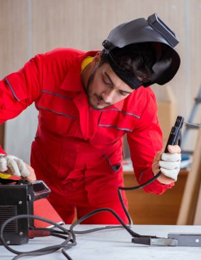 Kaynak tabancası elektrot ve kask takan genç bir tamirci.