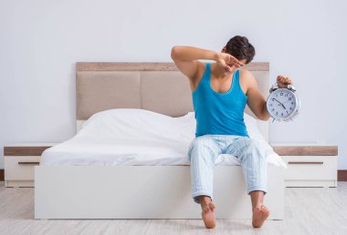 Genç adam yatakta uyanıyor.
