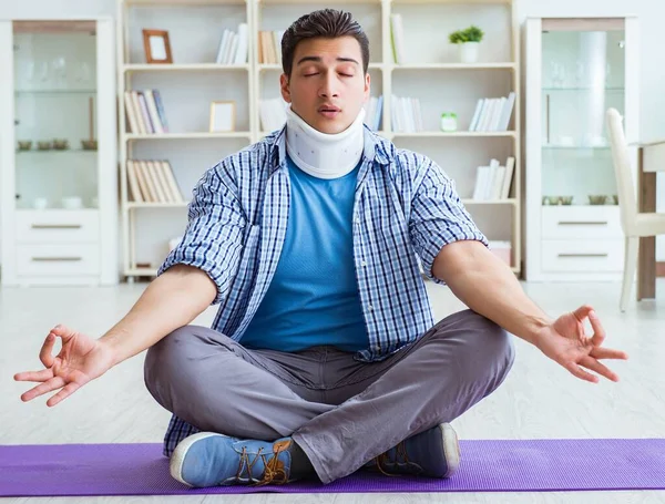 Hombre con lesión en el cuello meditando en casa en el suelo —  Fotos de Stock