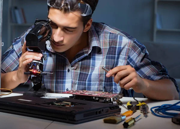 Reparatör försöker reparera bärbar dator med miscroscope — Stockfoto