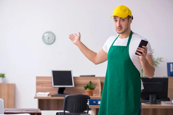 Junge männliche Auftragnehmer putzen das Büro — Stockfoto