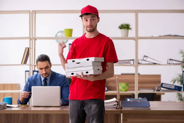Młody człowiek dostarcza pizzę do biura. — Zdjęcie stockowe