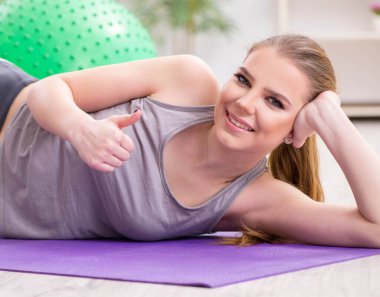 Spor salonunda denge topuyla egzersiz yapan genç bir kadın.