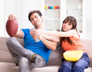 Adam karısıyla Amerikan futbolu seyrediyor.