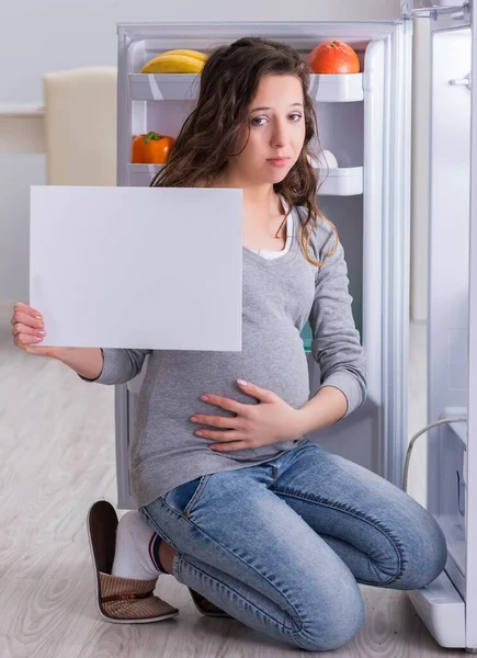 Pregnant woman near fridge with blank message — Stock Photo, Image