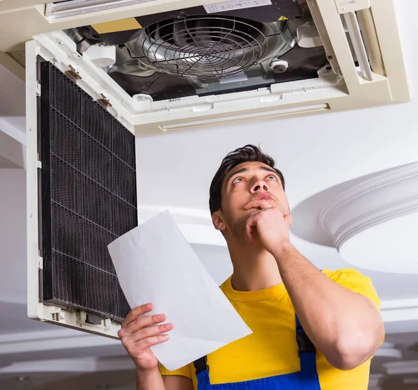 Repairman repairing ceiling air conditioning unit — Stock Photo, Image