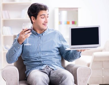 Genç adam evde şarap içiyor.