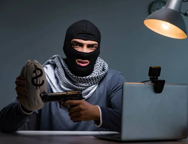 Terroristische inbreker met pistool werkend op computer — Stockfoto