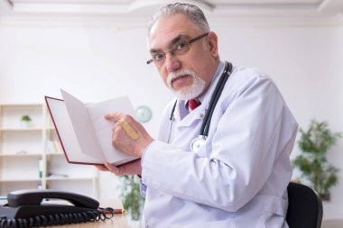 Klinikte çalışan yaşlı erkek doktor.