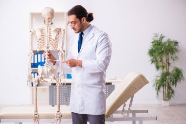 İskeleti olan genç erkek doktor.