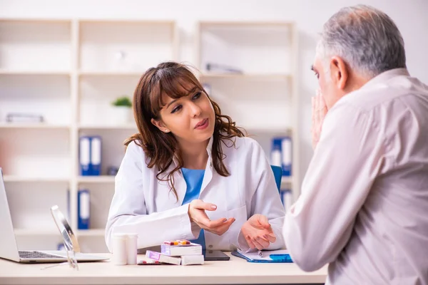 Anciano visitando a una joven doctora para cirugía plástica —  Fotos de Stock