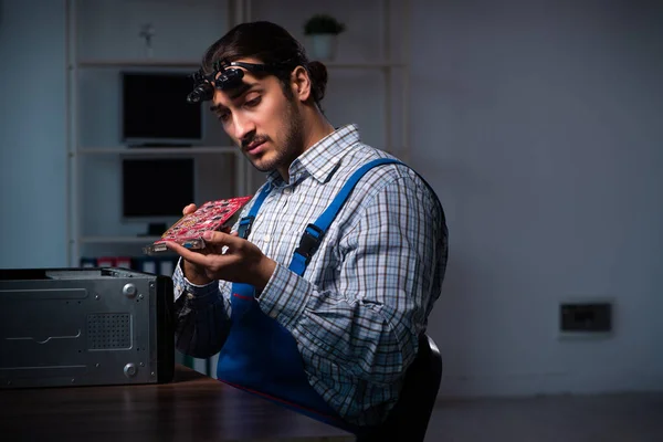 Νεαρός τεχνίτης επισκευάζει υπολογιστές στο εργαστήριο τη νύχτα — Φωτογραφία Αρχείου