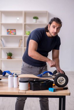 Kaykay tamir eden genç bir erkek tamirci.