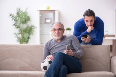 Baba oğul televizyonda maç izliyorlar.