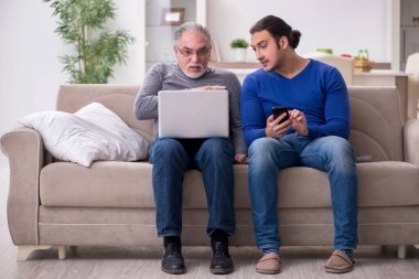 Baba oğul kanepede bilgisayar başında oturuyor.