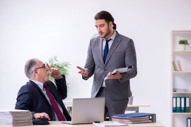 Eski patron ve genç asistanı ofiste çalışıyor.