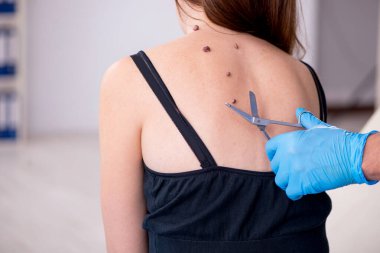 Genç bir kadın erkek doktor dermatoloğunu ziyaret ediyor.