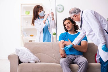 İki doktor hasta bir genci ziyaret ediyor.