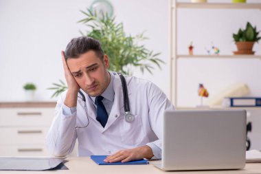 Klinikte çalışan genç erkek doktor.