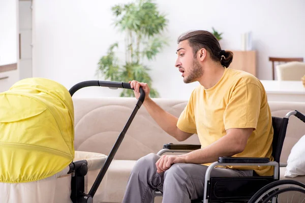 Młody mężczyzna wykonawca na wózku inwalidzkim opiekuje się noworodkiem — Zdjęcie stockowe
