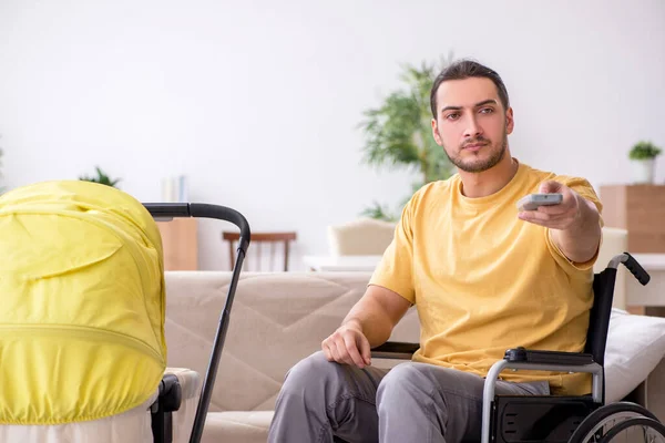 Jongeman aannemer in rolstoel op zoek naar pasgeborene — Stockfoto