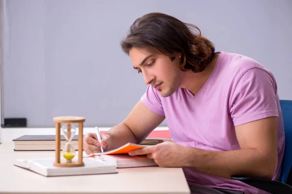 Young male student in the classroom at time management concept — Stock Photo, Image