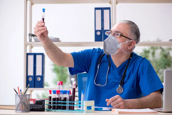 Oude mannelijke arts werkzaam in de kliniek — Stockfoto