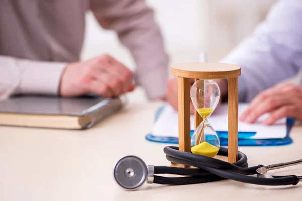 Gammal manlig patient besöker ung läkare i tid management concep — Stockfoto