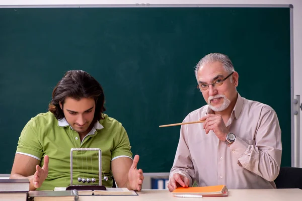 Старый профессор физик и молодой студент в классе — стоковое фото